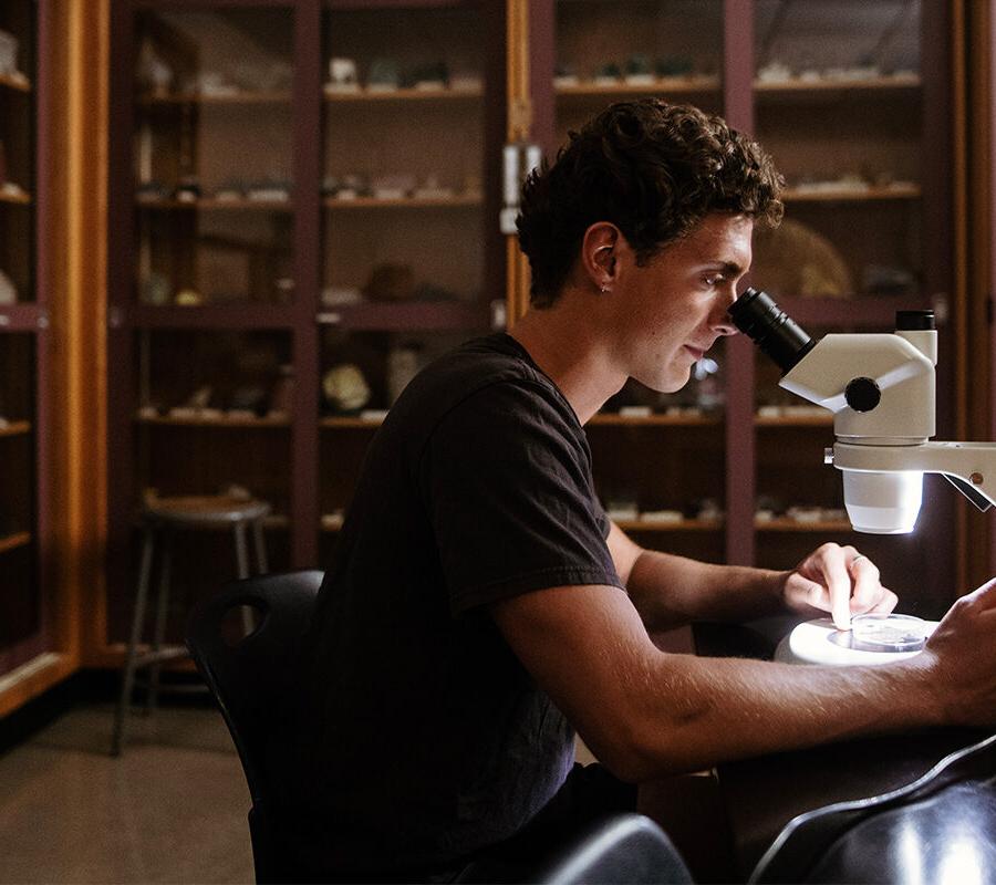 Biology student looks into a microscope.